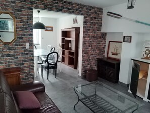 Ein Wohnzimmer mit Backsteinwand, einem Glastisch, einer Ledersofa und einem Kamin.