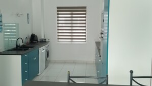 A modern kitchen with a washing machine, a sink, and a window with blinds. - Family home close to the sea (Penmarch)