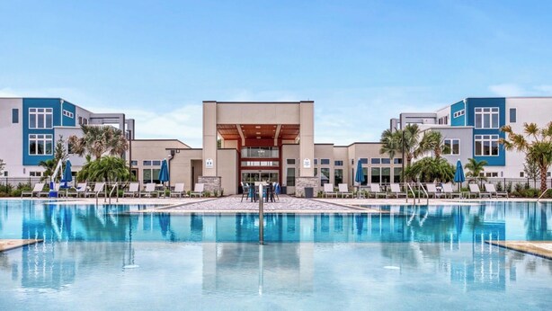 Un hotel con una piscina grande, sillones reclinables y palmeras.