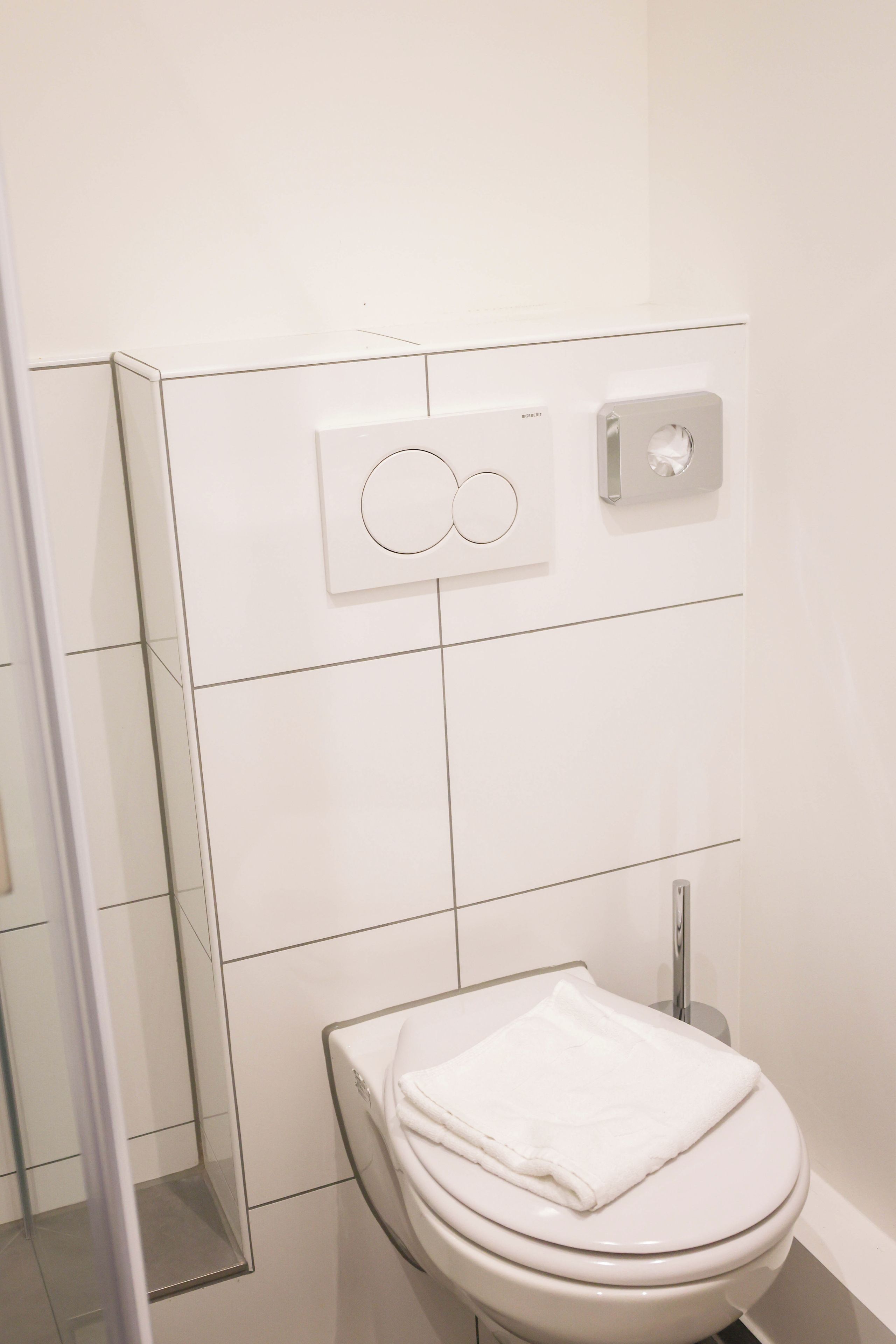 A bathroom with a toilet, a towel, and a hand dryer.