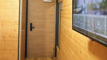 Ein Hotelzimmer mit Holzvertäfelung, einem an der Wand befestigten Fernseher und einem Schreibtisch mit Fernbedienung.
