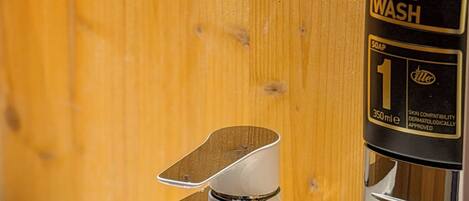 A hand wash dispenser with a soap dispenser attached to a chrome faucet.