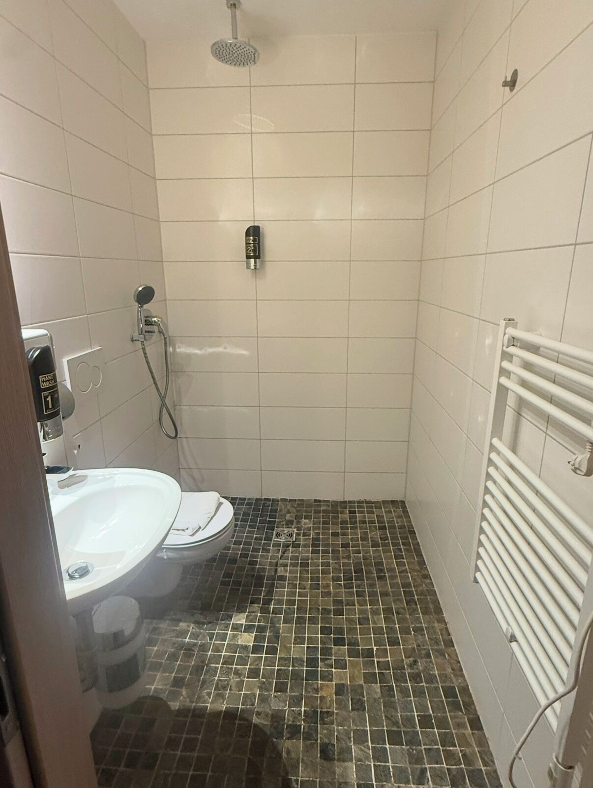 Un baño pequeño con ducha, inodoro y lavamanos.