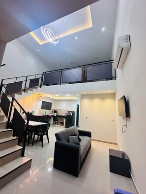 Un amplio salón con una escalera que lleva a un piso superior, un comedor y una cocina.