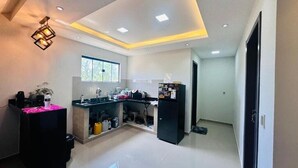 Eine moderne Küche mit schwarzem Arbeitsplatz, Spüle und Kühlschrank. Ein Fenster sorgt für natürliches Licht, und eine Deckenleuchte ist installiert.