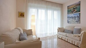 Una sala de estar con dos sofás, una lámpara y un cuadro en la pared.