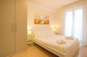 Quarto com cama, mesas de cabeceira, guarda-roupa e um quadro na parede.