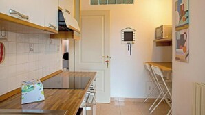 Una cocina compacta con microondas, un refrigerador pequeño y una encimera de madera.