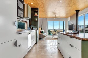 Une cuisine moderne dotée d’un îlot central, d’appareils électroménagers intégrés et offrant une vue sur l’extérieur.