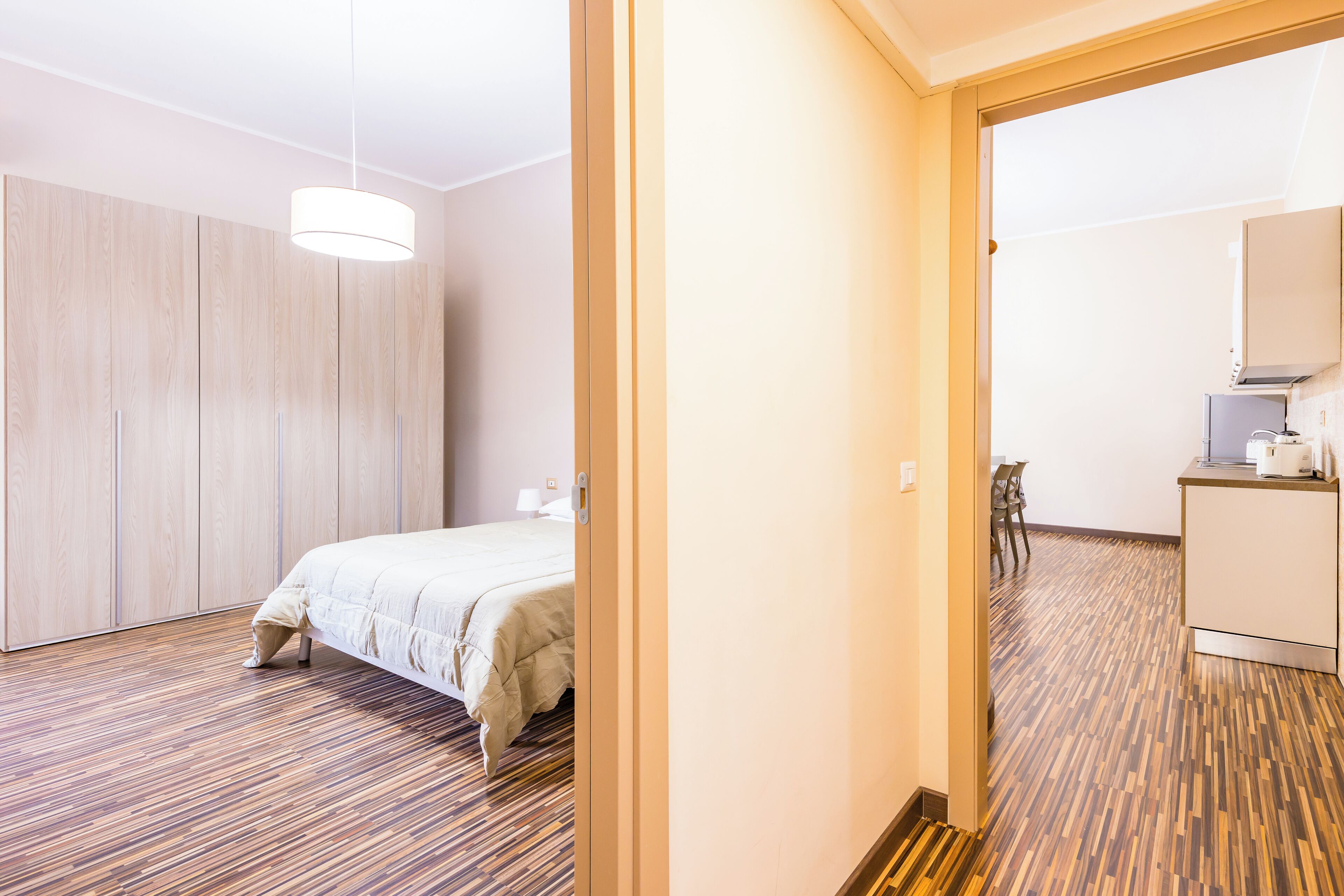 Camera d'albergo con un letto, un armadio in legno e un angolo cottura.