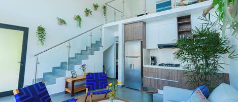 Ein modernes Interieur mit Treppe, Sitzgelegenheit, Küche und einer großen Pflanze.