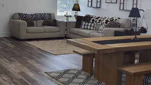 A spacious living room with a wooden floor, two sofas with patterned cushions, a wooden coffee table, a chandelier, and a ceiling fan. - Farmhouse Retreat
5 minutes from Ruoff Music Center (Pendleton)