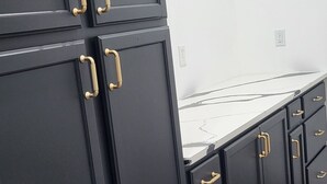 A room with dark wooden cabinets, gold handles, and a white countertop. - Farmhouse Retreat
5 minutes from Ruoff Music Center (Pendleton)