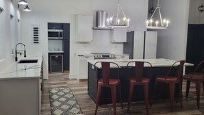 A modern kitchen with a central island, pendant lighting, and a dining area with chairs. - Farmhouse Retreat
5 minutes from Ruoff Music Center (Pendleton)