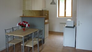 Una cocina pequeña con mesa, sillas, refrigerador y ventana.