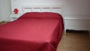 Un dormitorio con cama, mesita de noche y mesilla auxiliar.