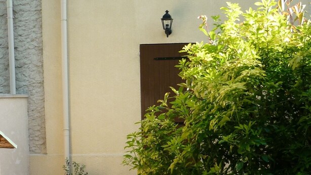 Una casa con entrada de baldosas, una planta en maceta y un aplique de pared.