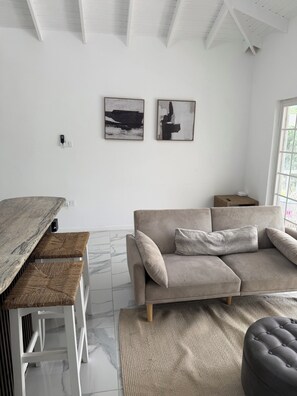 A modern living room with a sectional sofa, a wooden coffee table, and a marble floor. - NEW Luxury Home  in Cap Estate St Lucia near Golf Course, Beach walking Distance (Gros Isleat Cap Estate)