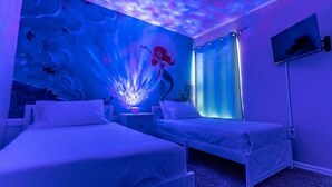 Een kamer met twee bedden, een plafondventilator, een muurschildering en een televisie.