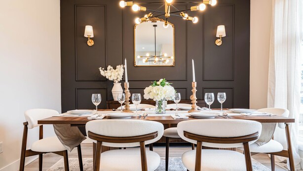 Ein Esszimmer mit dunkler Wandverkleidung, einem großen Spiegel und einer Chandelier.