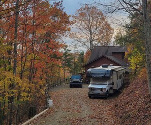 A campsite with a covered RV and a car parked on a leaf-covered path. - Quiet Cabin in Murphy, NC 20 min drive to Blue Ridge, GA & Copperhill, TN (Murphy)