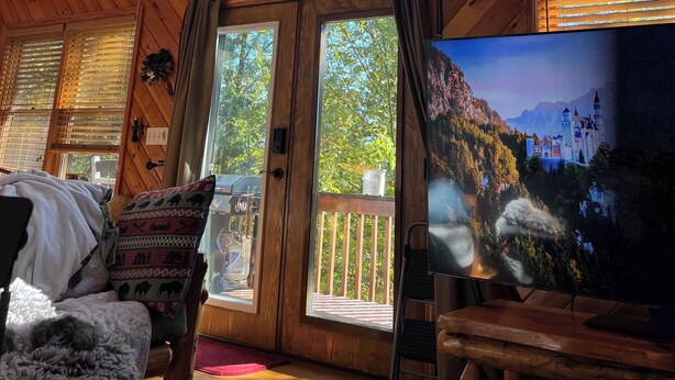 Een chalet met grote ramen, een houten plafond, een televisie en een gezellige zithoek.