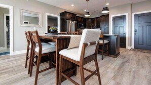 A modern kitchen with dark wood cabinets, stainless steel appliances, and a central island with bar stools. - BWV 24-6 Abiding Place (Branson)