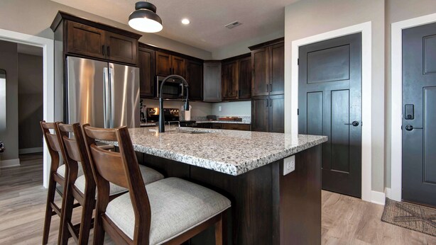 A modern kitchen with dark wood cabinets, stainless steel appliances, and a granite countertop. - BWV 24-6 Abiding Place (Branson)