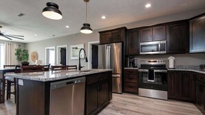 A modern kitchen with dark wood cabinets, stainless steel appliances, and a granite countertop island. - BWV 24-6 Abiding Place (Branson)