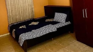 Un dormitorio con cama, aire acondicionado, armario y techo estampado.