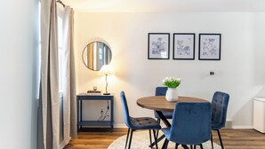 A dining area with a round wooden table, four blue chairs, a small side table with a lamp, and three framed botanical prints on the wall. - Cute & Cozy Ferndale Duplex (Ferndale)
