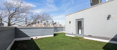 Une terrasse avec une pelouse artificielle, une porte et une vue sur le panorama urbain.