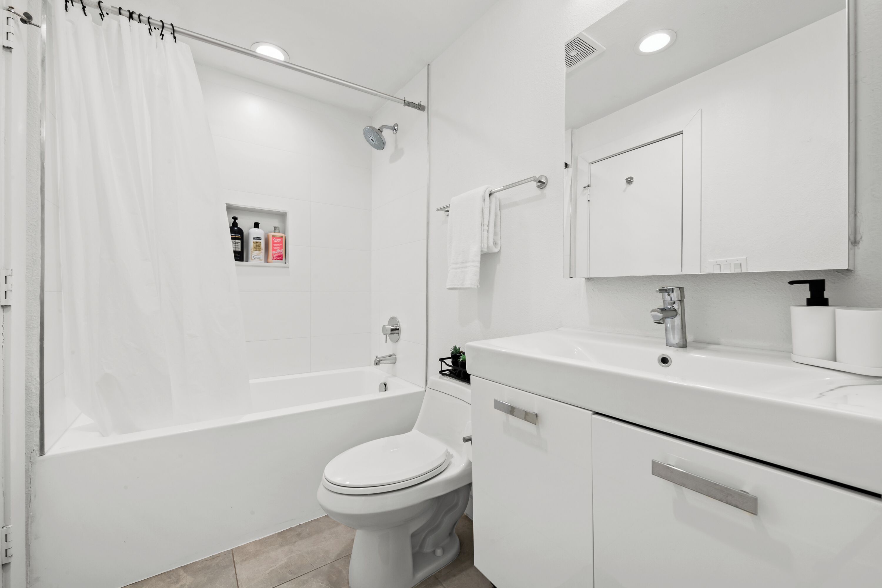 A modern bathroom with a bathtub, toilet, and vanity.