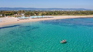 A beach with clear turquoise water, a boat, and beach umbrellas. - Masseria Belvedere - Eight Bedroom Villa, Sleeps 16 (Carovigno)