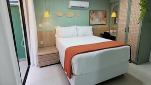 A bedroom with a bed, bedside lamps, an air conditioner, and a wall-mounted artwork. - Flat Aurea Cabo Branco 50m do mar 104 (João Pessoa)