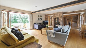 A spacious living area with a sofa, a coffee table, and a fireplace. - Little Hare Oast -  large home for smaller groups with amazing views (Rye)