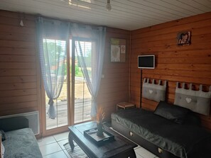 A room with a bed, a small table, a TV, and a window with curtains. - Chalet in a peaceful setting (Rochesson)