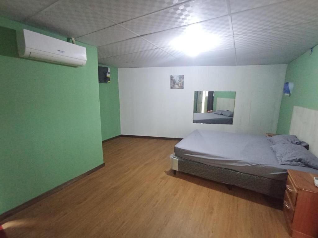 Una habitación con una cama, un escritorio pequeño y un equipo de aire acondicionado en la pared.