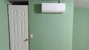 A room with a closed door, a white air conditioning unit mounted on the wall, and a visible electrical outlet. - Casa de Huespedes Noche de Luna (San Salvador)