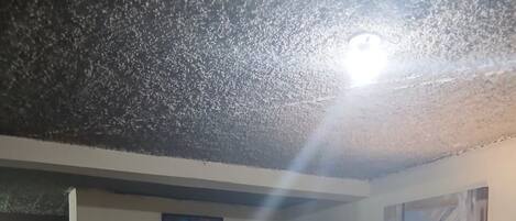 Uma sala de estar com um sofá escuro, uma televisão em um móvel e um quadro na parede.