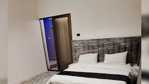 A hotel room with a bed, a chair, and a patterned floor. - Tala Villa - Dead Sea (Swemeh)