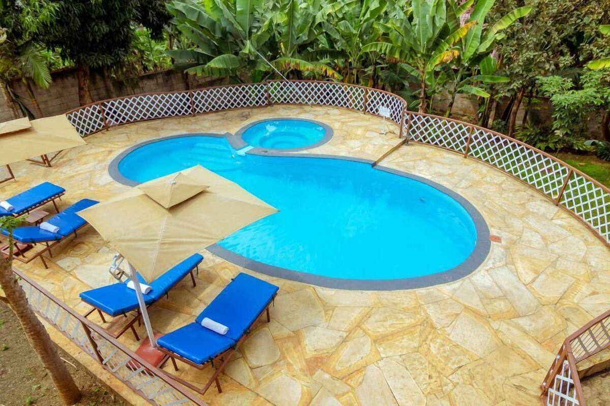 A swimming pool with a heart-shaped design, surrounded by a stone deck and a white lattice fence.