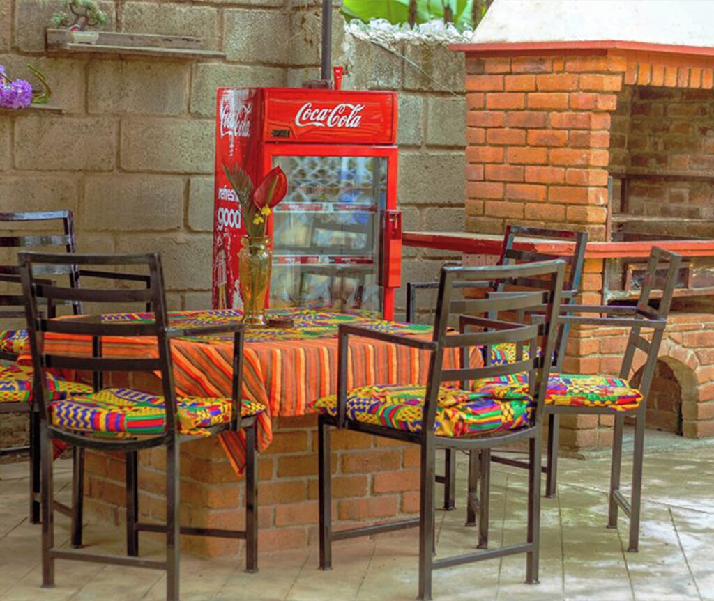 An outdoor seating area with a brick wall, a Coca-Cola vending machine, and a brick oven.