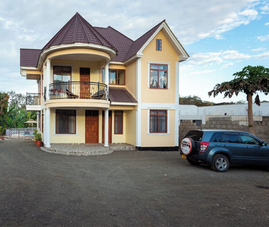 A two-story house with a balcony, a driveway, and a parked car.