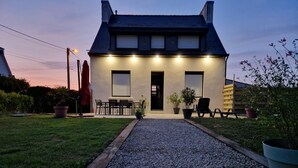 A two-story house with a gravel driveway leading to a front door, a patio with outdoor furniture, and potted plants. - Completely renovated Breton house - Walking distance to the beach - Sleeps 8 (Penmarch)