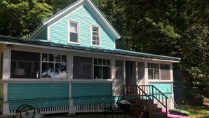 A two-story house with a covered porch and a small deck.