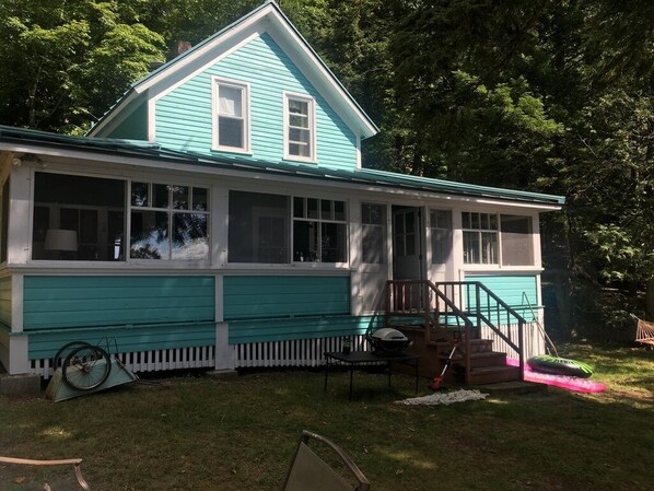 A two-story house with a covered porch and a small deck. - Classic Waterfront Maine Cottage (Madison)