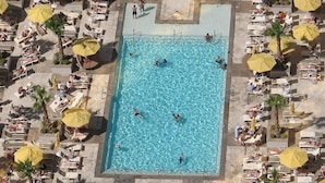 An aerial view of a swimming pool surrounded by sun loungers and umbrellas, with people swimming and relaxing. - MGM Signature Penthouse with Balcony + incredible Sphere View in Las Vegas Strip (Las Vegas)