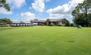 A golf course with a clubhouse in the background. - Modern Spacious Condo with no step access, pools, fishing, games and golf! (Branson)