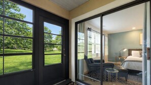 A modern hotel room with a large sliding glass door leading to a balcony, a bed with a nightstand, a small table, and a chair. - Modern Spacious Condo with no step access, pools, fishing, games and golf! (Branson)